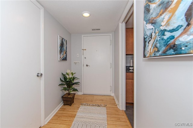 corridor with light hardwood / wood-style floors and a textured ceiling