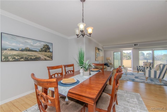 dining space with light hardwood / wood-style floors, an inviting chandelier, and crown molding