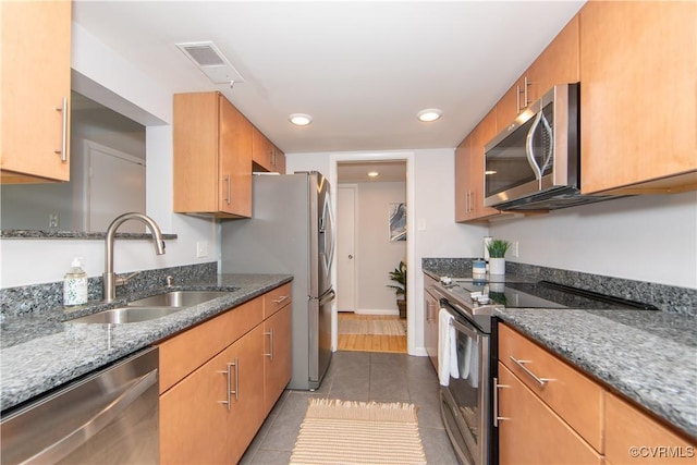 kitchen featuring sink, dark tile patterned floors, stainless steel appliances, and stone counters