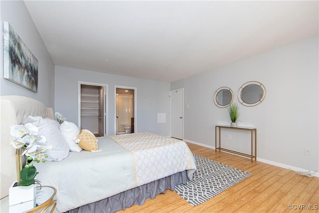 bedroom with connected bathroom, a spacious closet, a closet, and hardwood / wood-style flooring