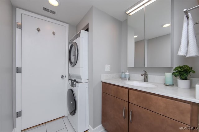 laundry area featuring sink, light tile patterned flooring, and stacked washer / drying machine