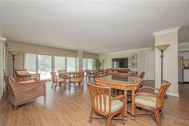 dining space with a textured ceiling, light wood-type flooring, and crown molding