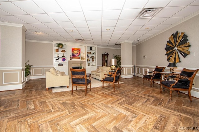 living room with built in shelves, crown molding, and parquet flooring