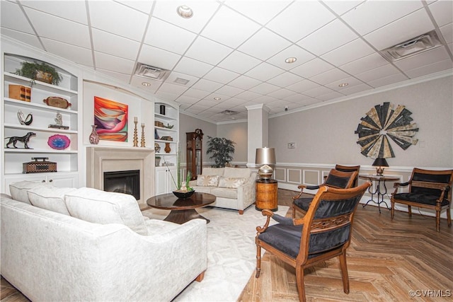 living room featuring a paneled ceiling, built in shelves, parquet floors, and crown molding