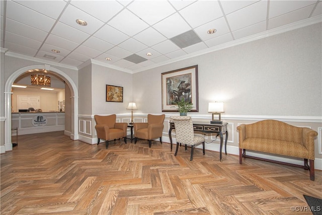 sitting room with ornamental molding and parquet flooring