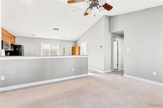 unfurnished living room featuring light carpet, high vaulted ceiling, sink, ceiling fan, and a textured ceiling