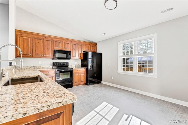 kitchen featuring light stone counters, sink, black appliances, and lofted ceiling