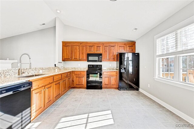 kitchen with black appliances, light stone countertops, sink, and vaulted ceiling