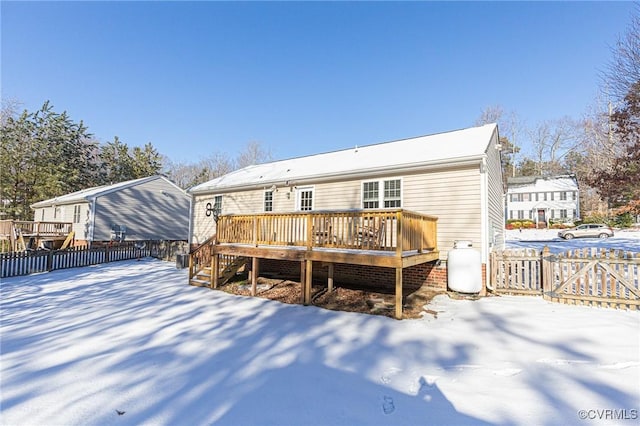 snow covered back of property with a deck