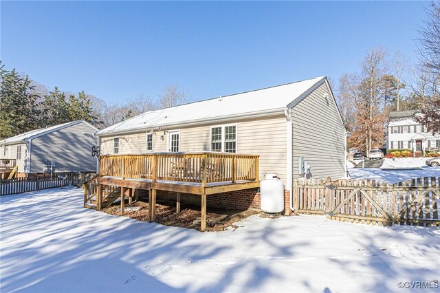 snow covered rear of property with a wooden deck