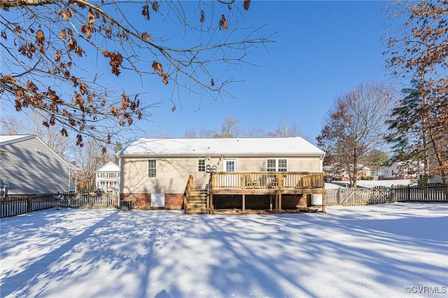 snow covered back of property with a deck