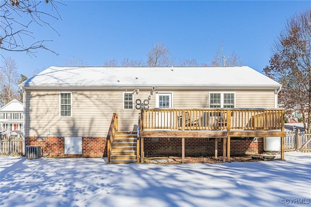 snow covered back of property with a wooden deck