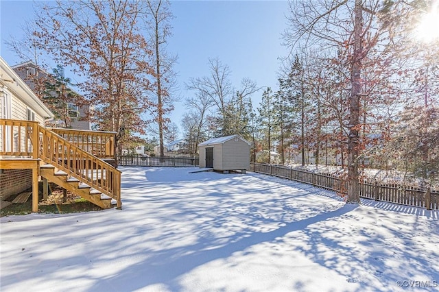 yard covered in snow featuring a storage unit and a deck