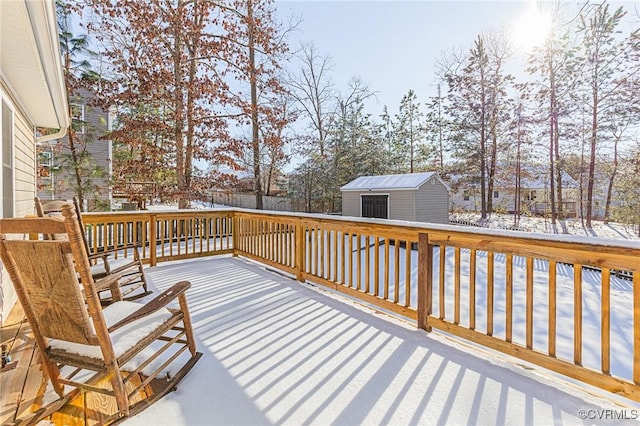 snow covered deck featuring a storage shed