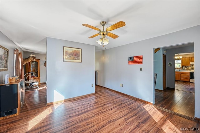 spare room featuring dark hardwood / wood-style floors and ceiling fan with notable chandelier