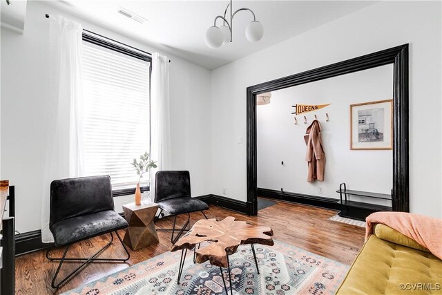 living area with wood-type flooring and a notable chandelier