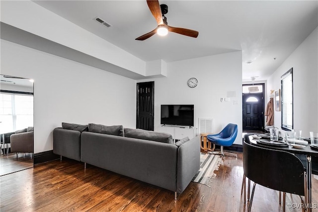 living room featuring ceiling fan and dark wood-type flooring