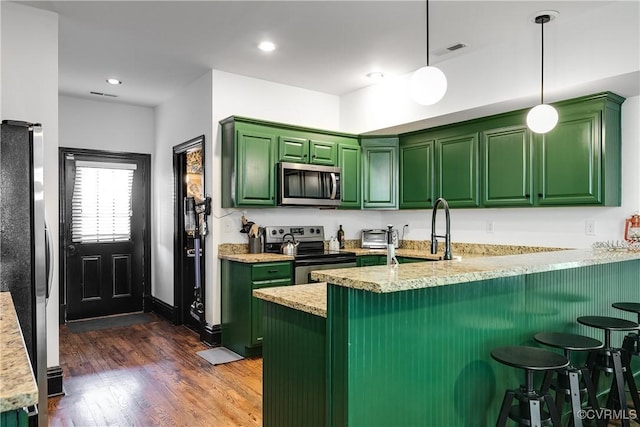 kitchen with decorative light fixtures, a kitchen breakfast bar, kitchen peninsula, and appliances with stainless steel finishes