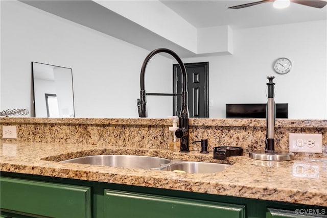 kitchen featuring ceiling fan, green cabinets, light stone counters, and sink