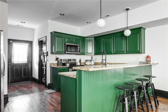 kitchen featuring kitchen peninsula, appliances with stainless steel finishes, dark hardwood / wood-style flooring, and green cabinets