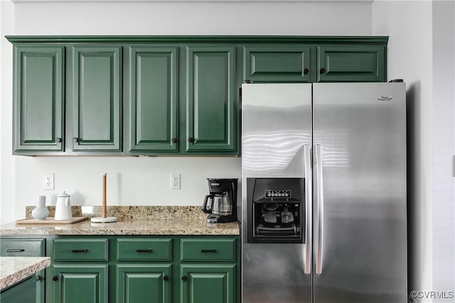 kitchen with green cabinets, light stone countertops, and stainless steel refrigerator with ice dispenser