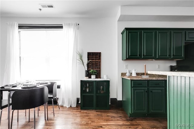 bar featuring dark hardwood / wood-style floors, a healthy amount of sunlight, and green cabinetry