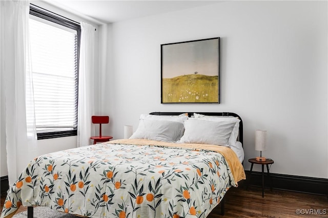 bedroom with dark hardwood / wood-style floors and a baseboard heating unit