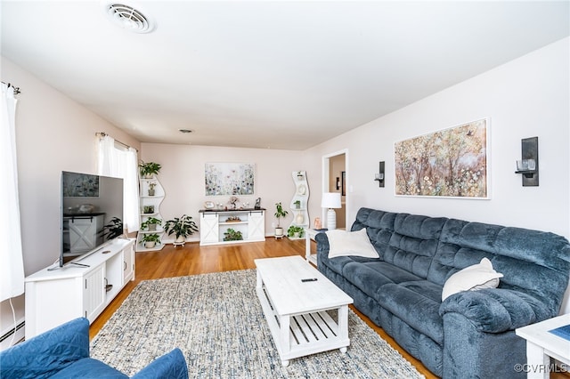 living room with baseboard heating and light hardwood / wood-style floors