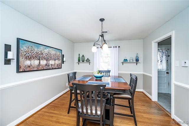 dining space with wood-type flooring and a notable chandelier