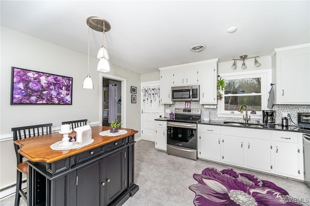 kitchen with a baseboard heating unit, stainless steel appliances, white cabinetry, and decorative light fixtures