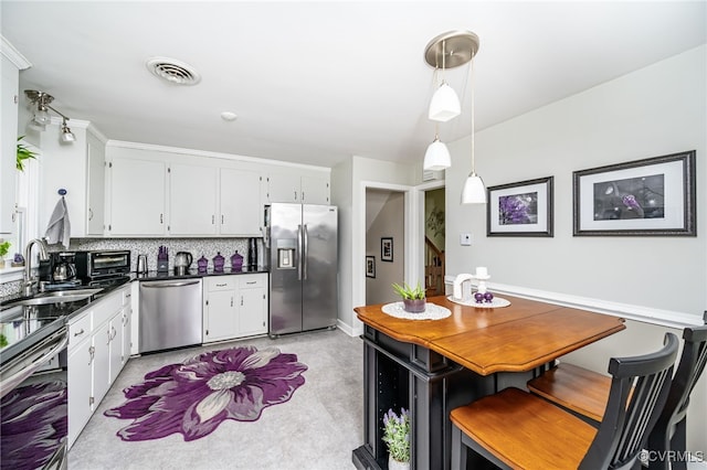 kitchen with decorative light fixtures, white cabinets, decorative backsplash, and stainless steel appliances