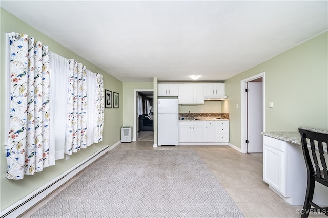 kitchen with white fridge, a baseboard radiator, white cabinets, light stone counters, and sink