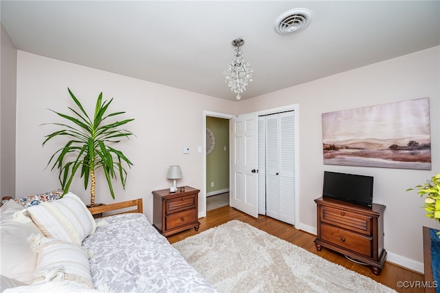 bedroom with an inviting chandelier, a closet, and wood-type flooring