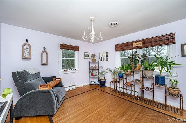 sitting room featuring hardwood / wood-style floors, plenty of natural light, a notable chandelier, and a baseboard radiator