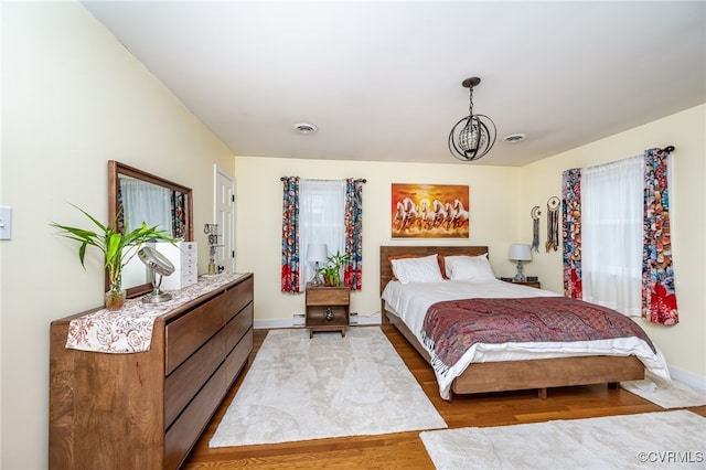 bedroom featuring an inviting chandelier, wood-type flooring, and multiple windows