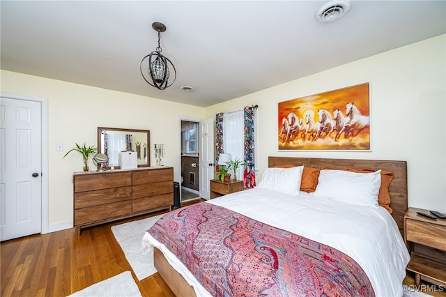 bedroom with wood-type flooring and an inviting chandelier