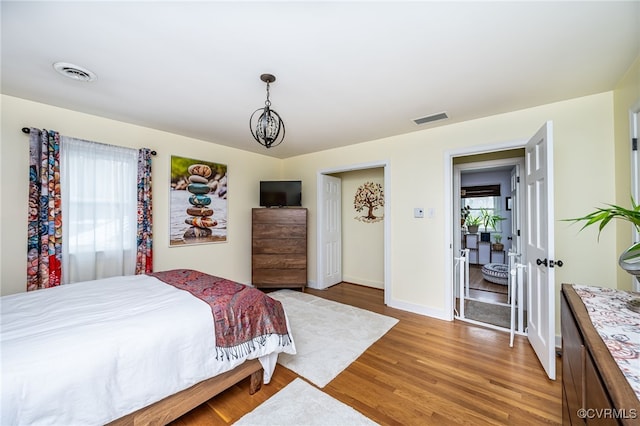 bedroom with a chandelier, hardwood / wood-style flooring, and multiple windows