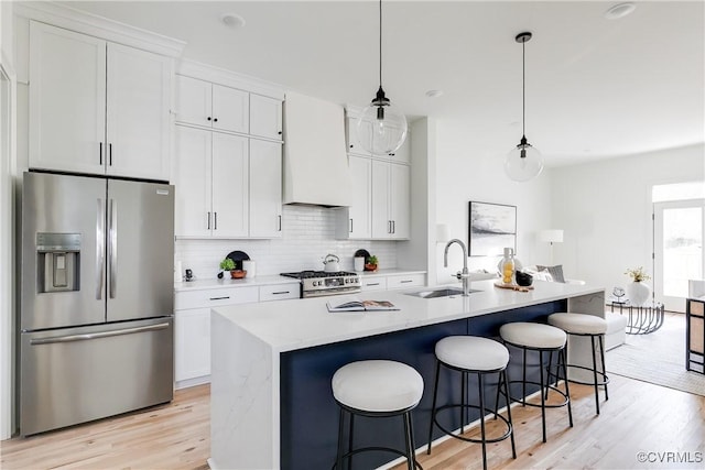 kitchen featuring white cabinetry, hanging light fixtures, a kitchen island with sink, and appliances with stainless steel finishes