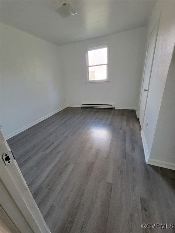 empty room with dark hardwood / wood-style floors and a baseboard radiator