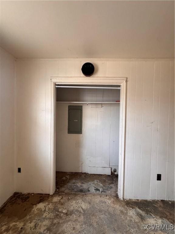 unfurnished bedroom featuring concrete floors, electric panel, and a closet