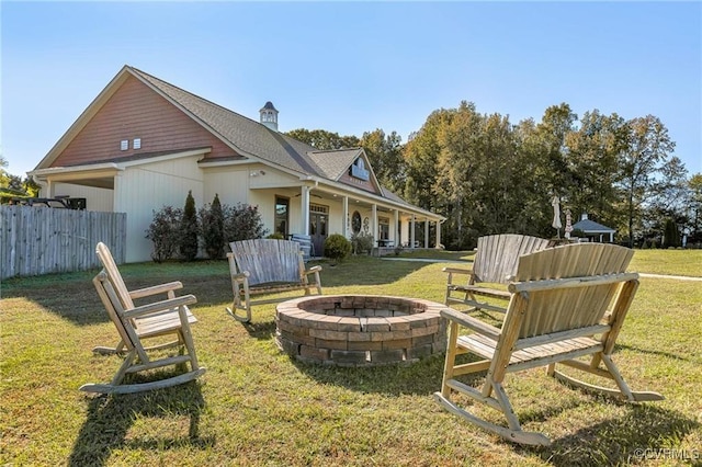 rear view of house with a yard, covered porch, and an outdoor fire pit