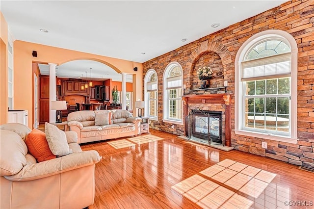 living room featuring light hardwood / wood-style floors, ornate columns, and a fireplace