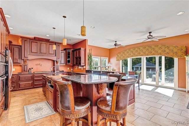 kitchen featuring pendant lighting, light tile patterned flooring, a breakfast bar area, and dark stone counters