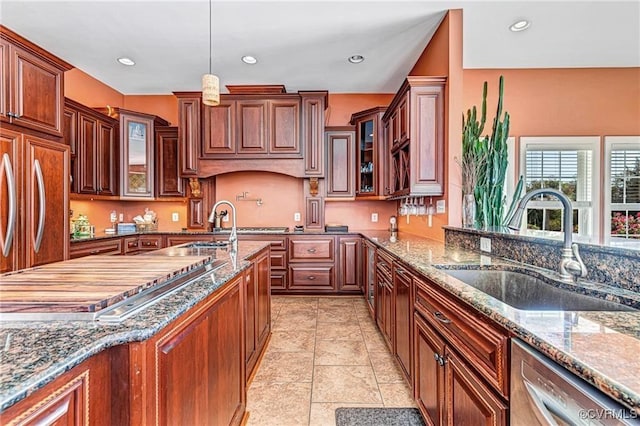 kitchen featuring dishwasher, hanging light fixtures, dark stone countertops, and sink