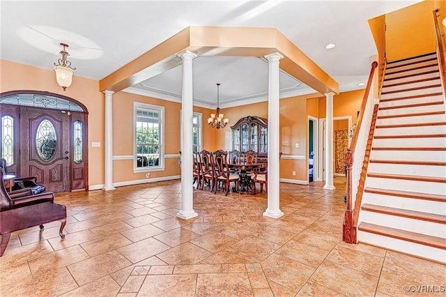 entryway with ornamental molding and an inviting chandelier