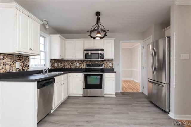 kitchen with white cabinets, appliances with stainless steel finishes, light wood-type flooring, and hanging light fixtures