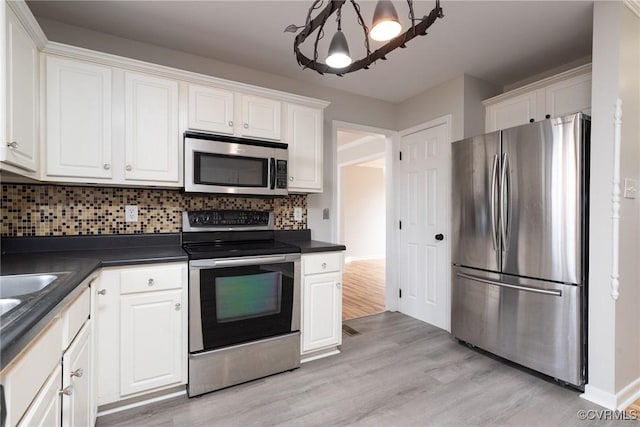 kitchen featuring decorative backsplash, light hardwood / wood-style flooring, white cabinets, and appliances with stainless steel finishes