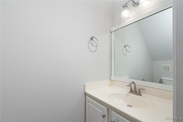 bathroom featuring vanity, toilet, and vaulted ceiling