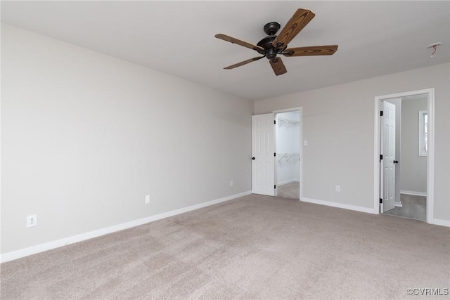 unfurnished bedroom featuring light carpet, a walk in closet, ceiling fan, connected bathroom, and a closet