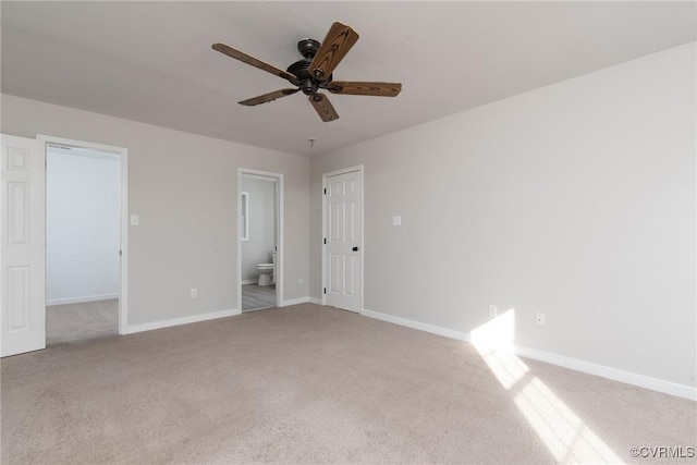 unfurnished bedroom featuring ceiling fan, a closet, light colored carpet, and ensuite bath